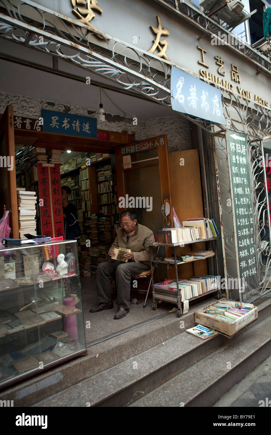 Mann sitzt außerhalb einer alten Buchhandlung in Doulun Road Shanghai china Stockfoto