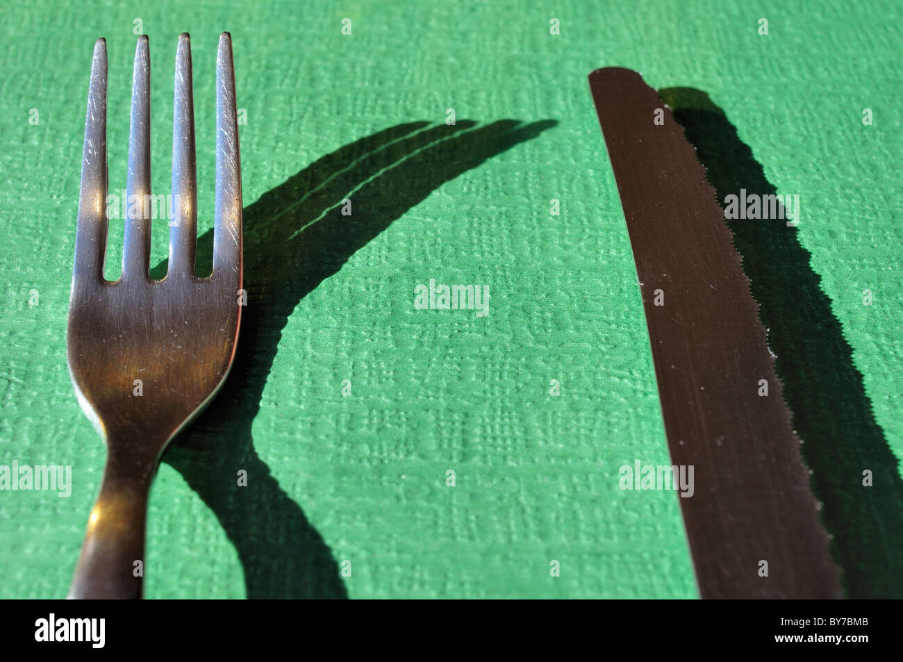 Messer und Gabel auf grünem Papier. Stockfoto