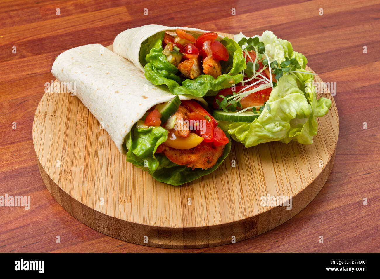 Würziges Huhn mit Salat und Salsa, eingehüllt in eine weiche Weizentortilla. Stockfoto