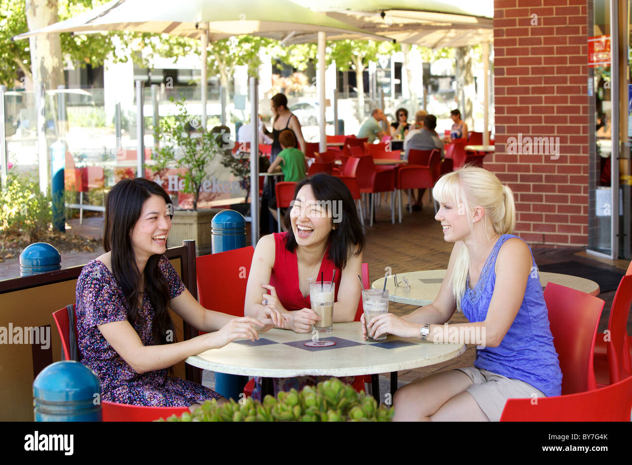 Australische Mädchen im Chat über einen Eiskaffee in einem Stadt-Café im Freien, in Adelaide, South Australia im Sommer Stockfoto