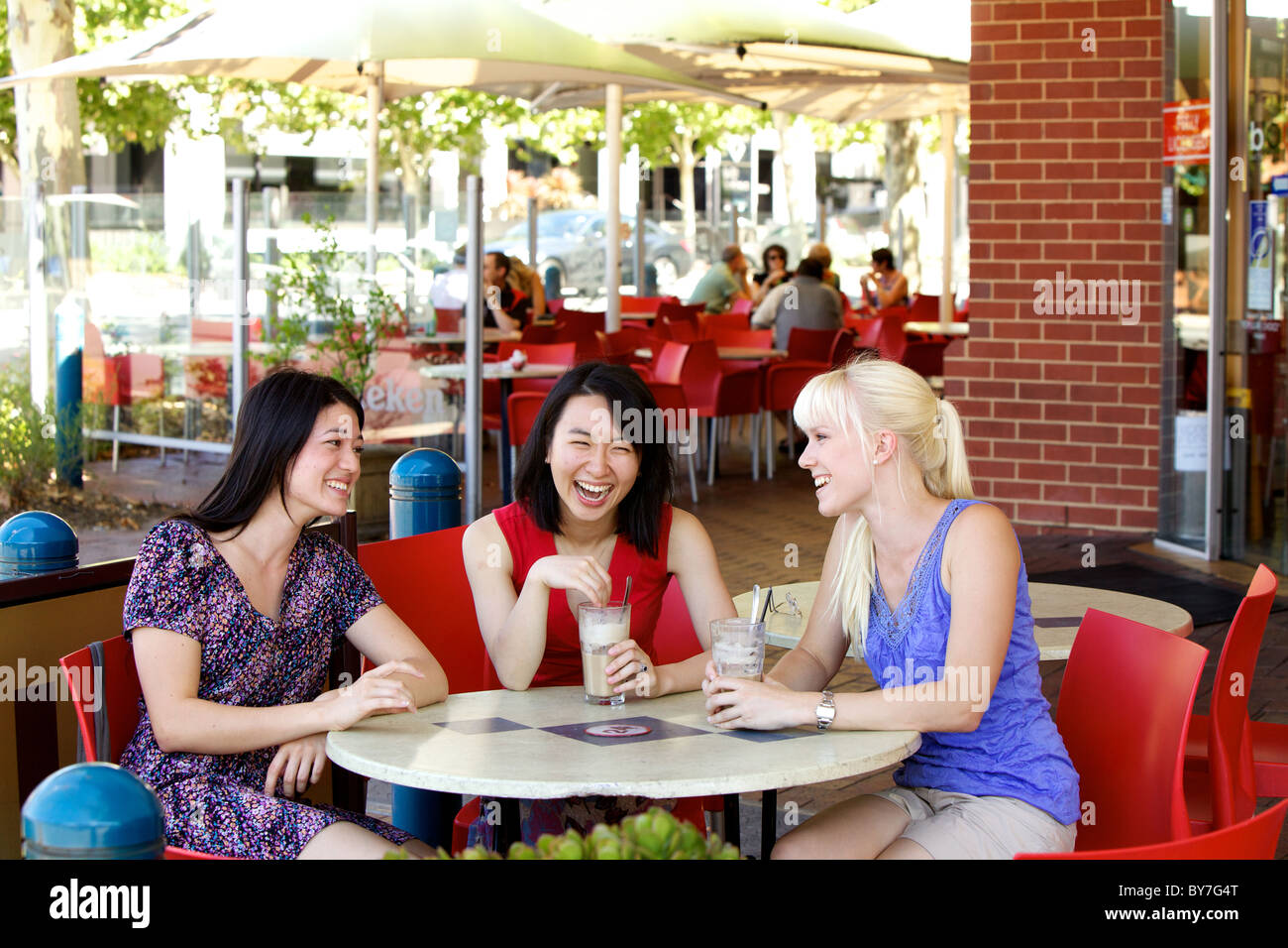 Australische Mädchen im Chat über einen Eiskaffee in einem Stadt-Café im Freien, in Adelaide, South Australia im Sommer Stockfoto