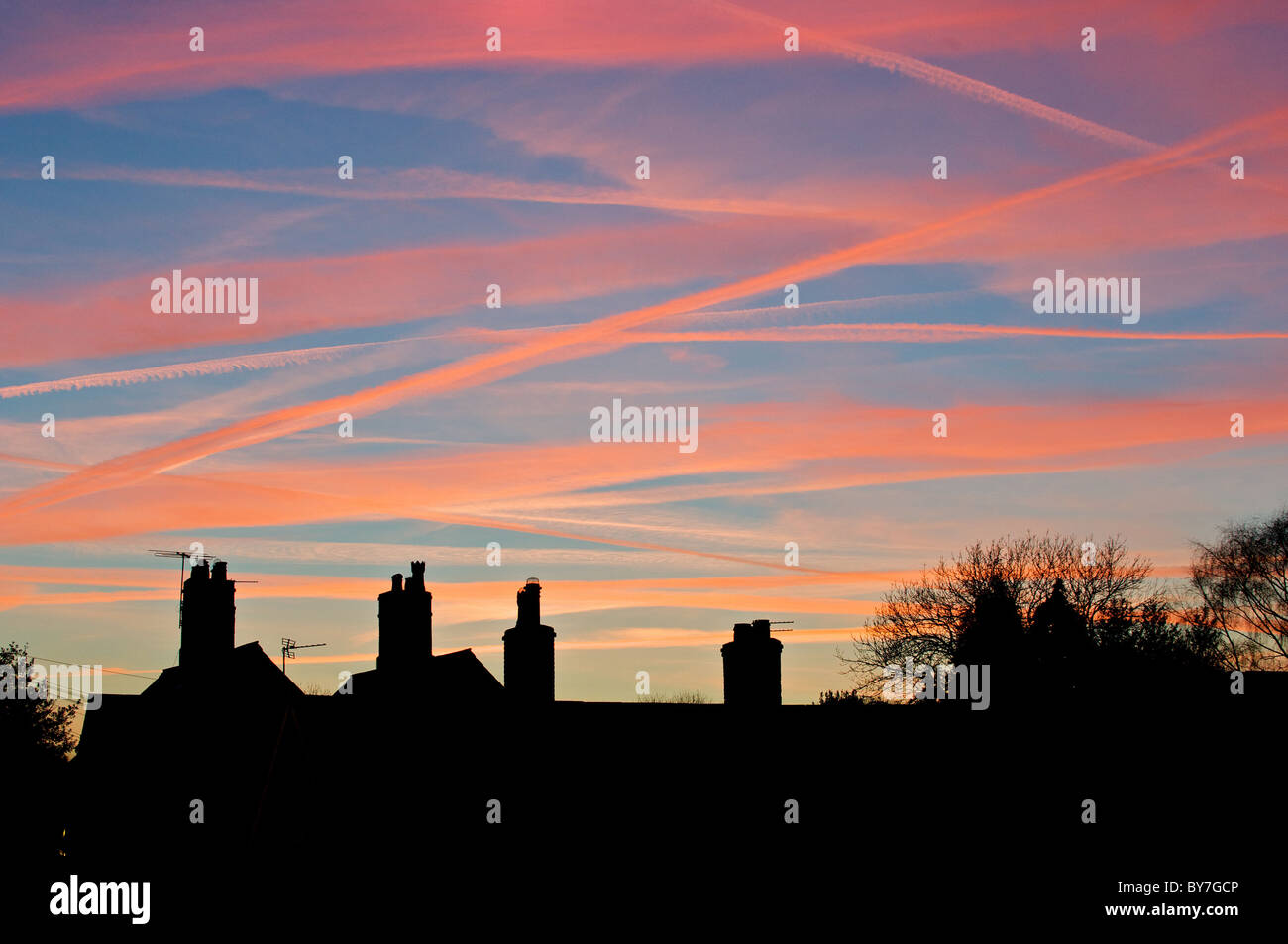 Flugzeug-Kondensstreifen durch die Einstellung Sonne und roten Himmel über diese Cheshire Schornstein Tops übertrieben Stockfoto