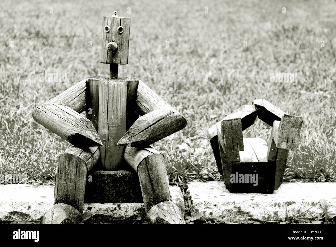 Holzfiguren sitzen in der Nähe von Wiese im Garten Stockfoto