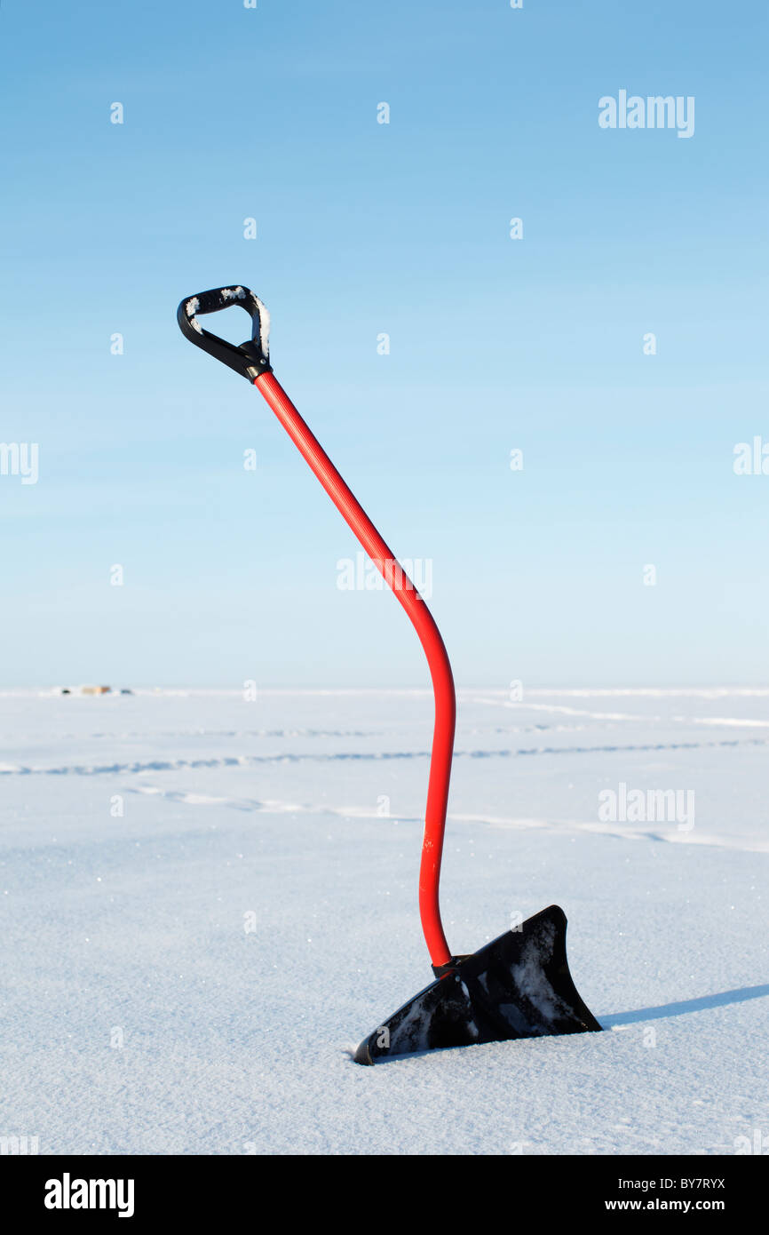 Eine Schneeschaufel mit einem gebogenen Griff in den Schnee. Stockfoto