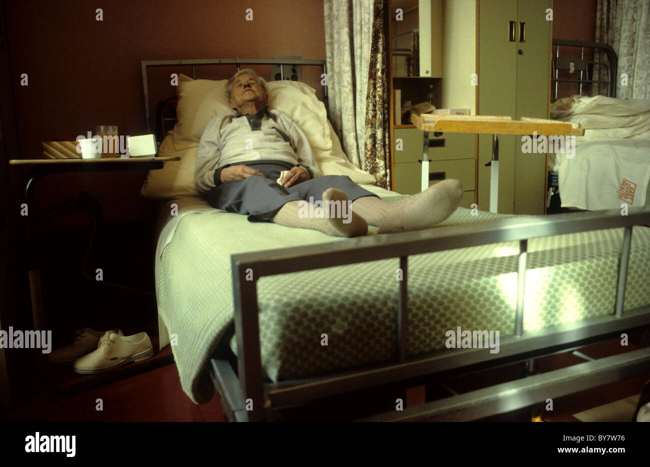 Ein Reifen älteren männlichen Patienten liegend warten auf ein Bett in einem NHS Spitalabteilung 1980er Jahre UK KATHY DEWITT Stockfoto