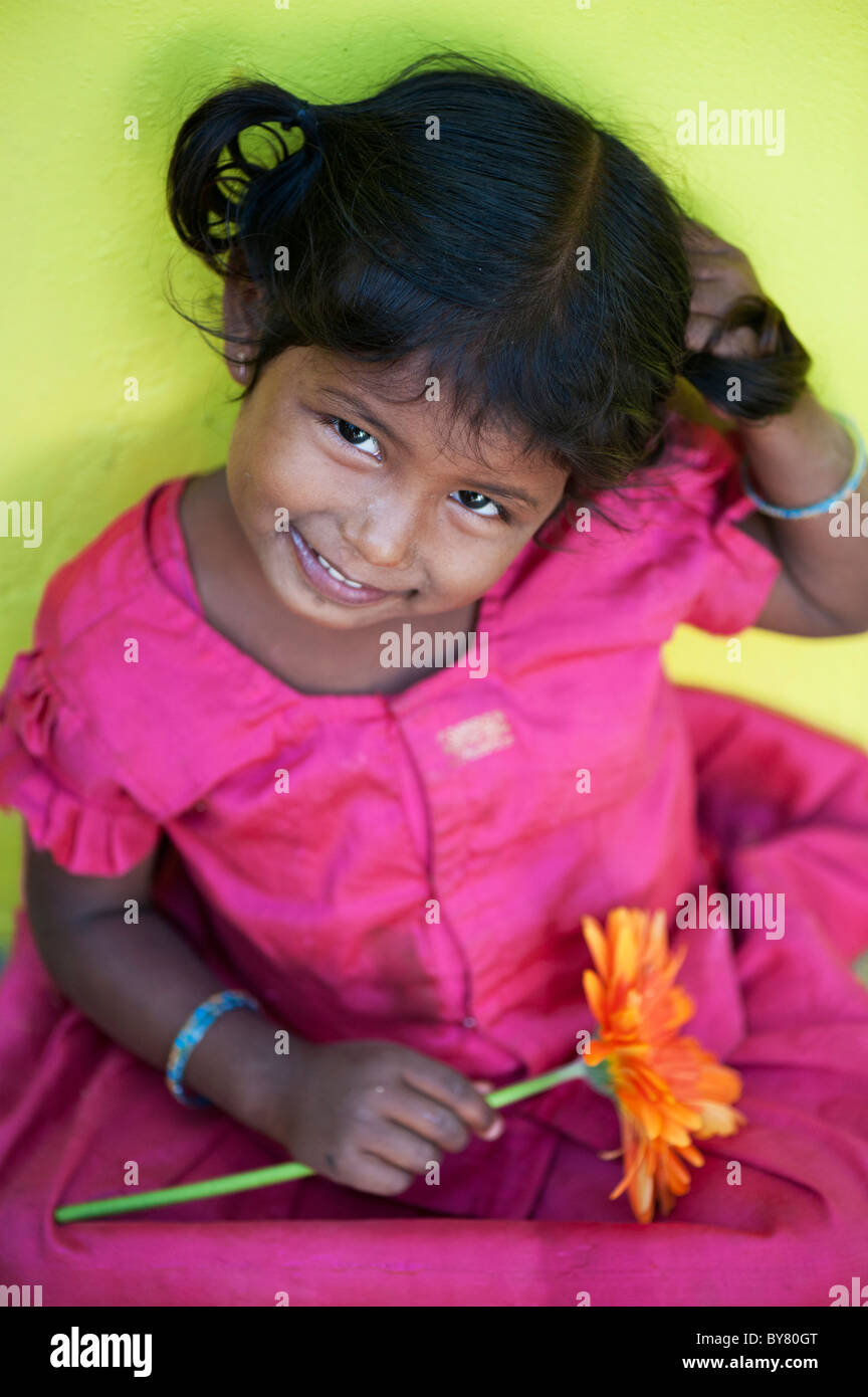 Junge indische Infant girl Holding Orange Gerbera Blume. Andhra Pradesh, Indien. Selektive konzentrieren. Stockfoto