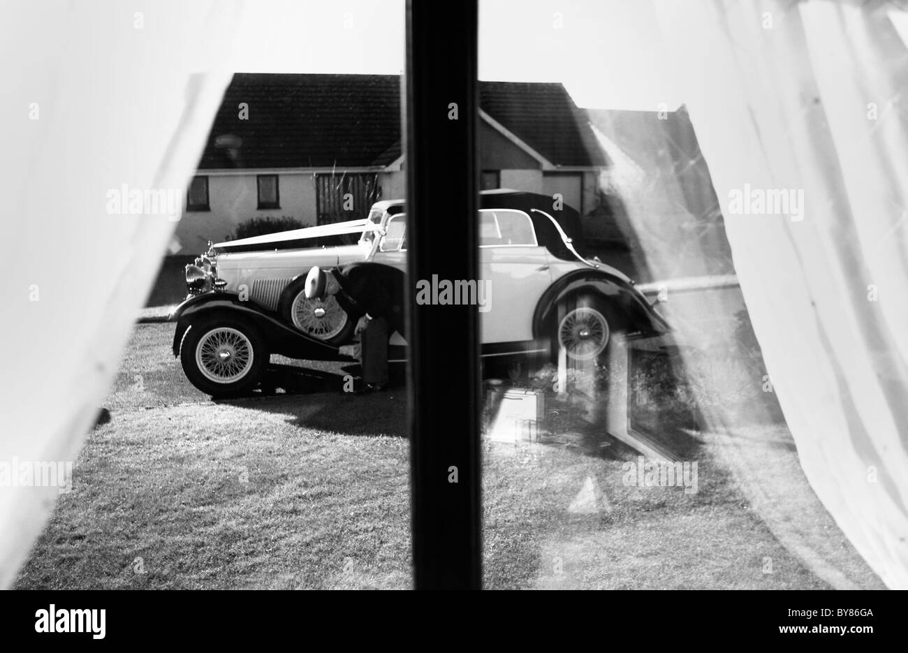 Ein Chauffeur reinigt ein Sunbeam Auto, während er darauf wartet, eine Braut zu ihrer Hochzeit fahren. Stockfoto