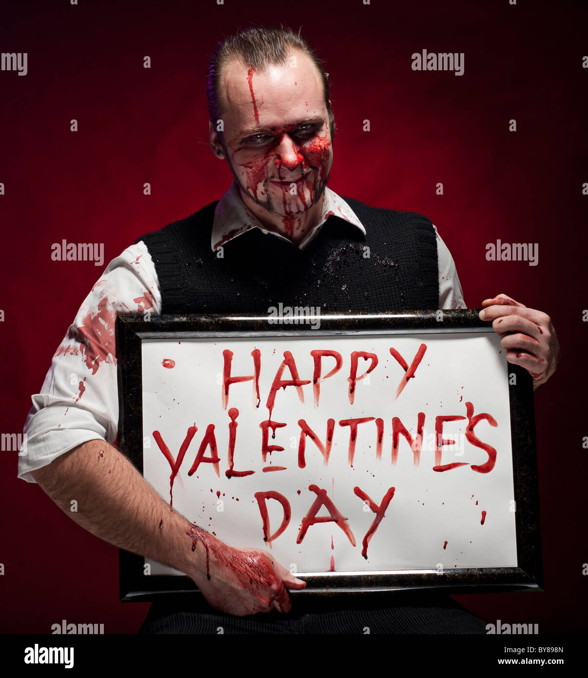 Mann hält ein happy Valentine Schild mit Blut geschrieben. Stockfoto