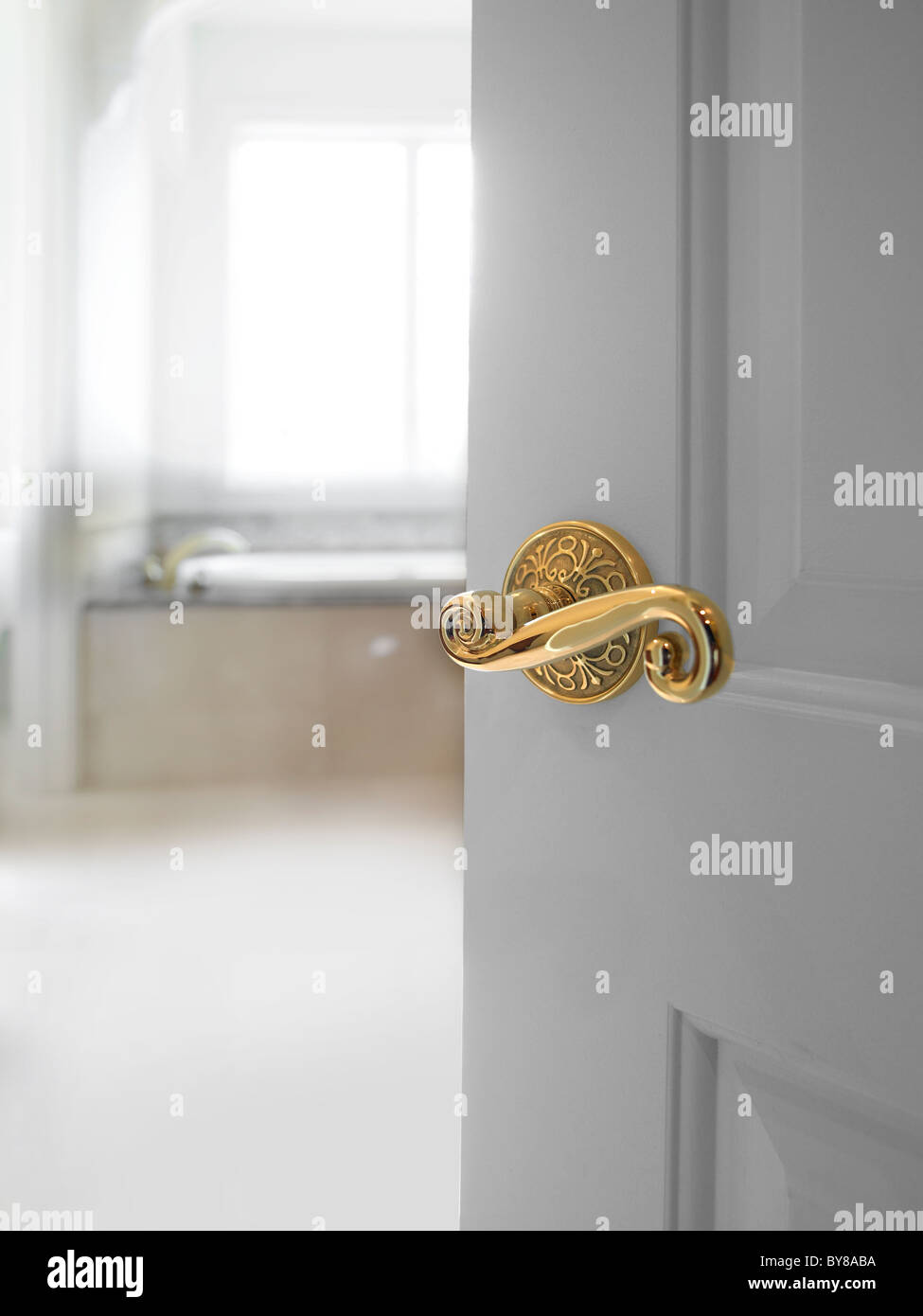 Tür mit ausgefallenen Knauf mit hellen weißen Bad teilweise offen Stockfoto