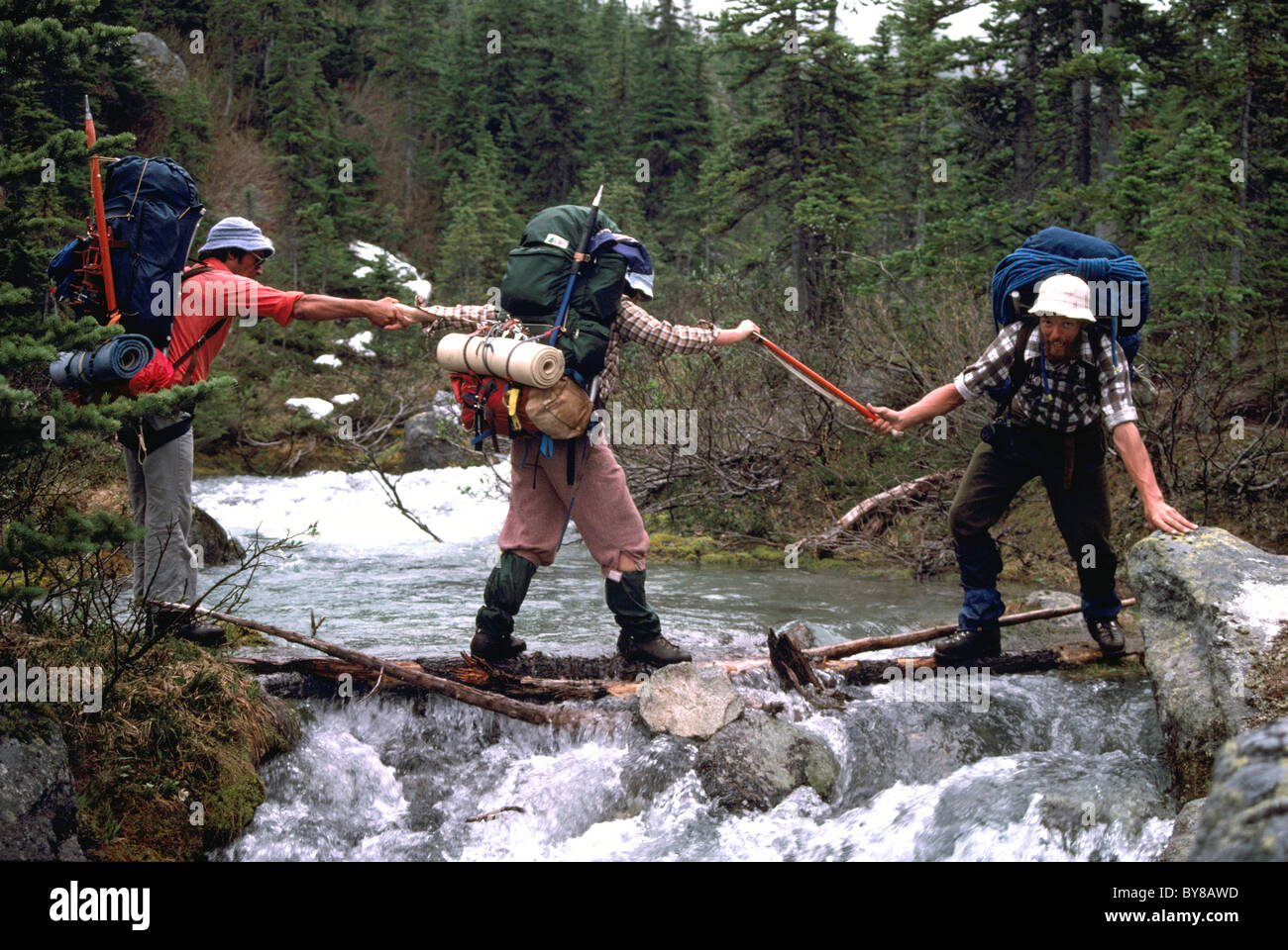 Wanderer / Backpackers helfen einander provisorischen Brücke über Mountain Creek in der Nähe von Pemberton, BC, Britisch-Kolumbien, Kanada Stockfoto