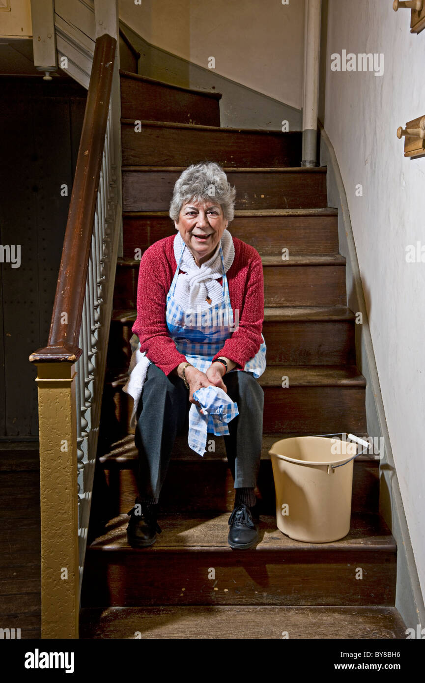 Alte Frau fertig Reinigung, sitzen auf den Stufen Treppen Stockfoto