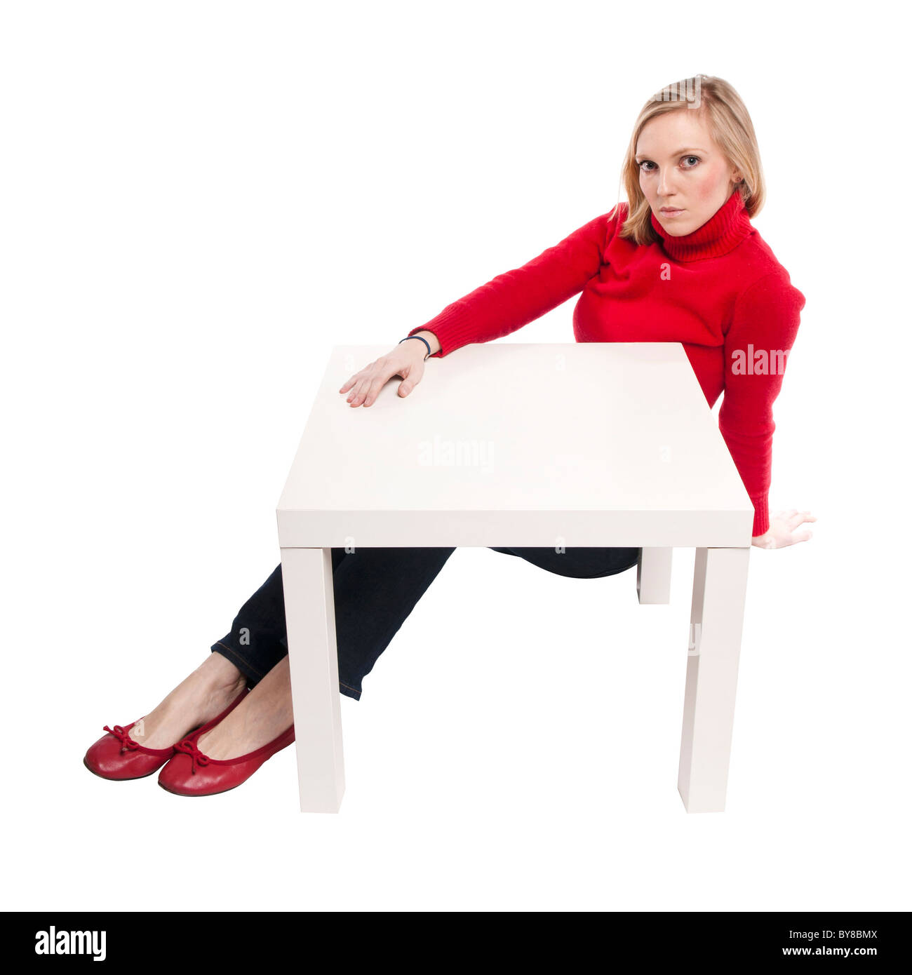 Junge Frau, Büroangestellter oder Student an lustigen kleinen Schreibtisch sitzen. Studio Foto, isoliert. Stockfoto