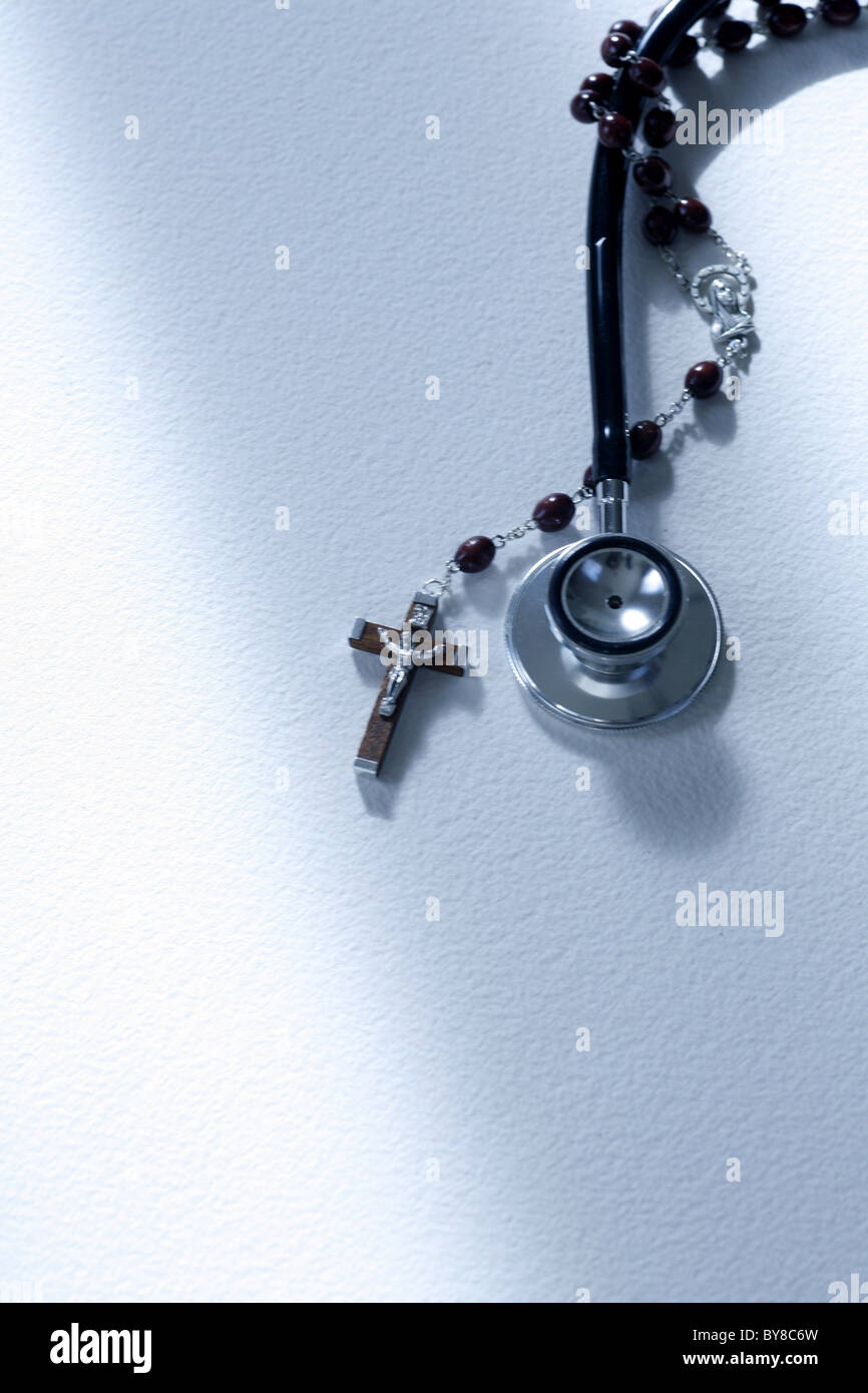 ein Stethoskop und einen Rosenkranz umschlungen, Religion gegen medizinische Wissenschaft Stockfoto