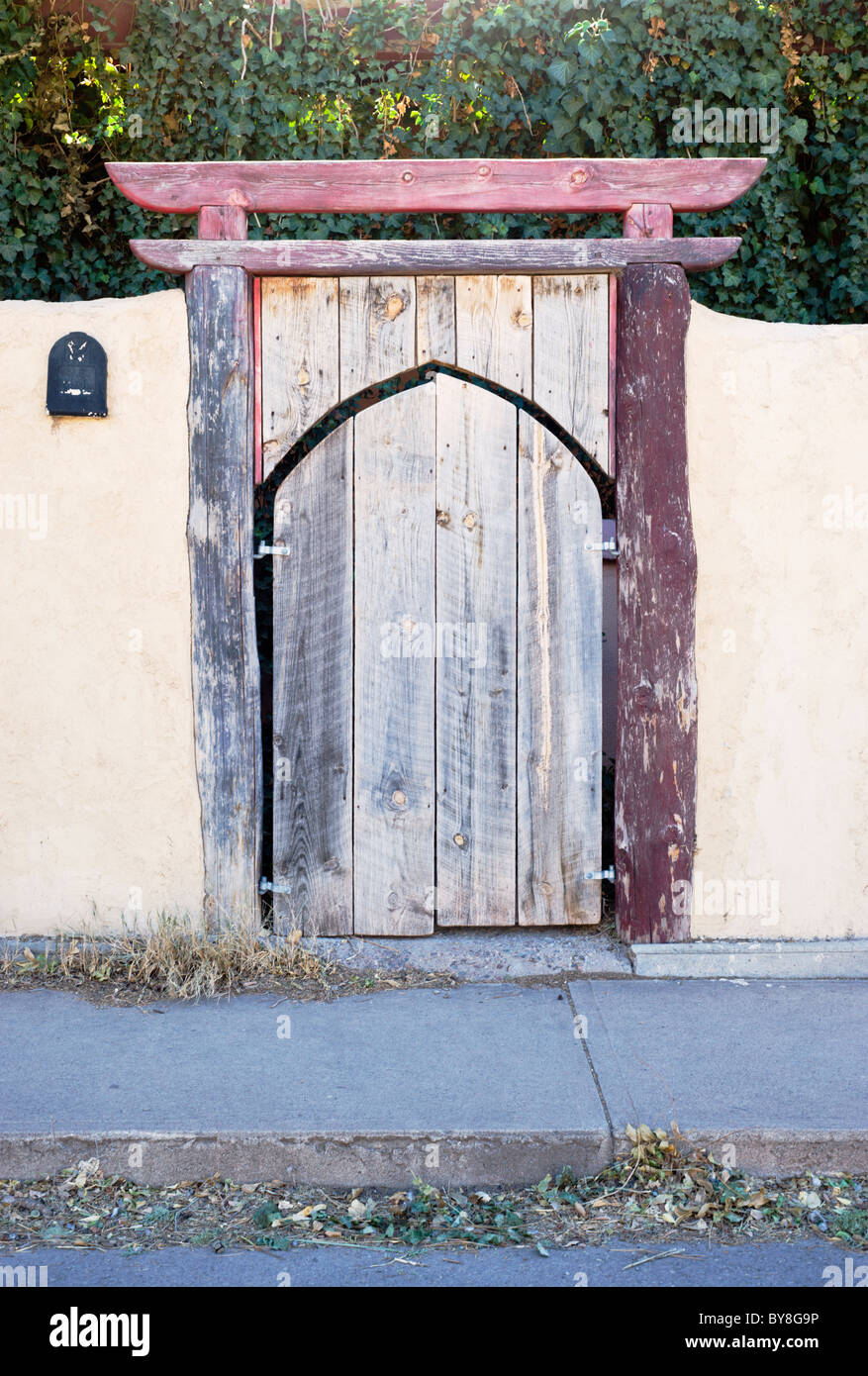 Ein verblassen Holz Tor eingelassen ein Adobe-Wand gefunden in Tularosa, New Mexico. Stockfoto