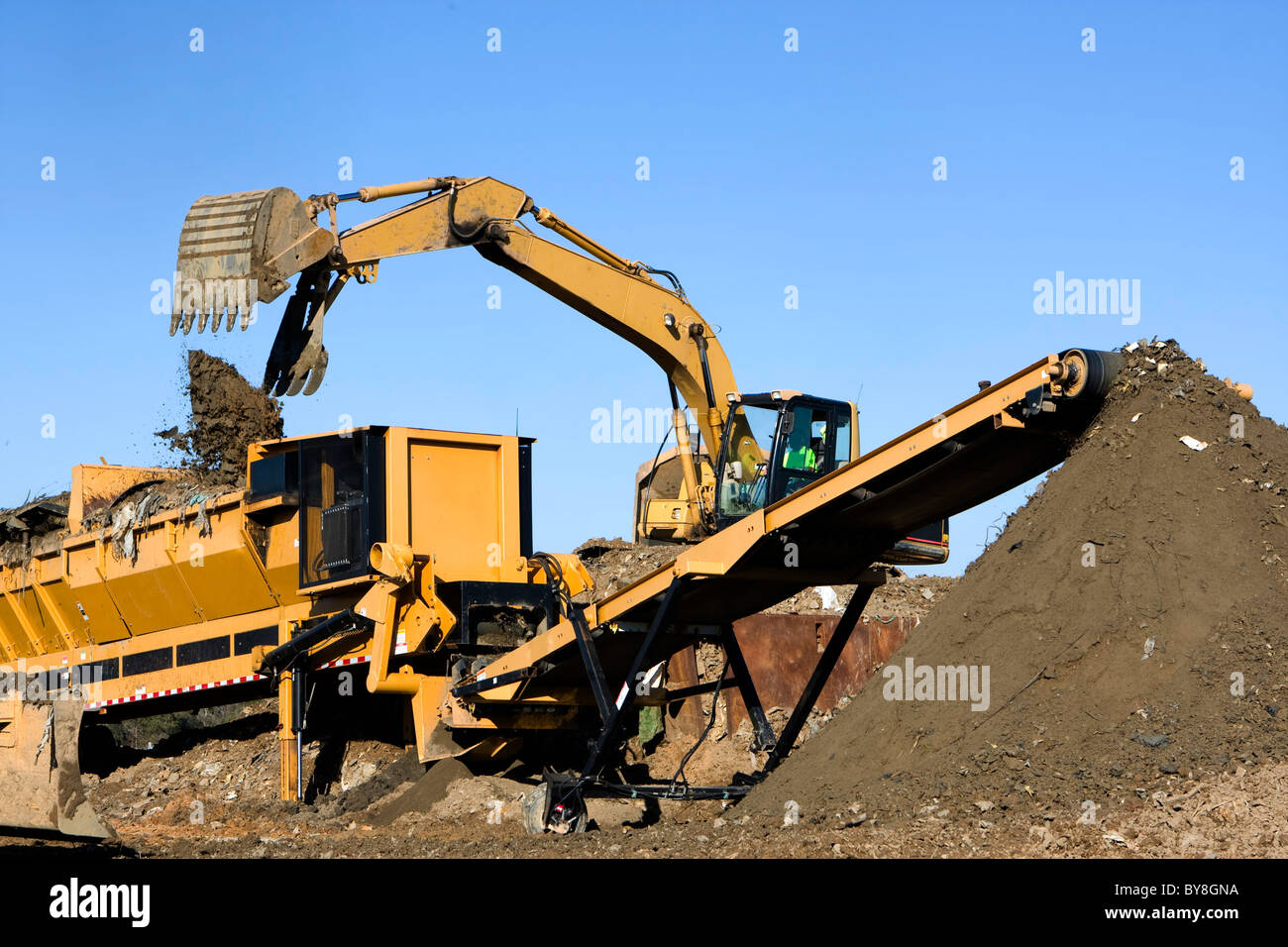 Front-End-Loader Deponien Deponie in einem Screener festen Abfälle aus gutem Boden zu trennen, die durch Förderband transportiert wird. Stockfoto