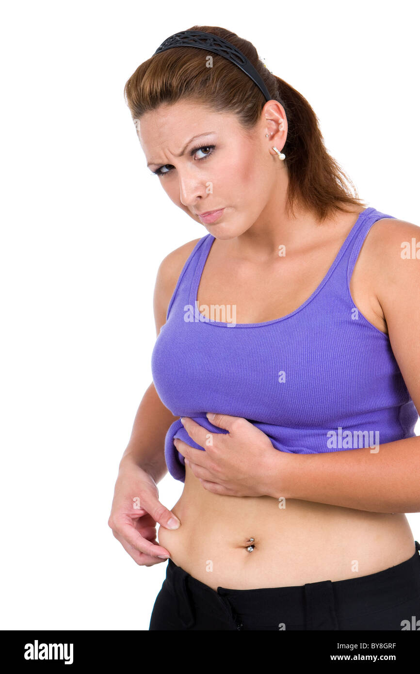 Eine junge Frau drückt die lose Fleisch rund um den Bauch und hat einen angewidert Blick auf ihrem Gesicht. Stockfoto