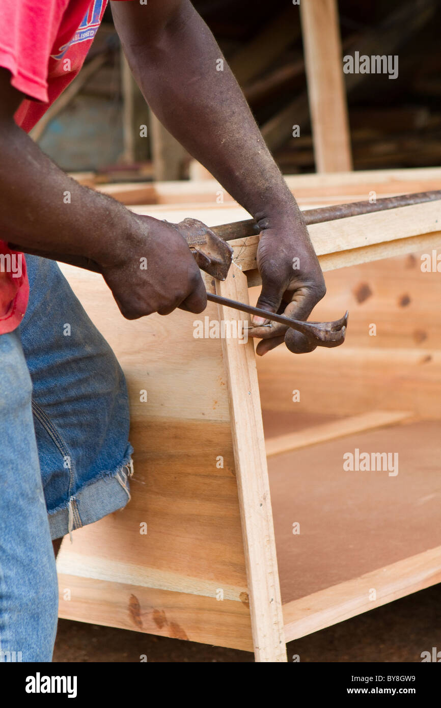 Schwarzer Mann nutzt Hammer und Nagel, um eine Kommode Truhe aus Zedernholz in Jamaika zu bauen. Stockfoto