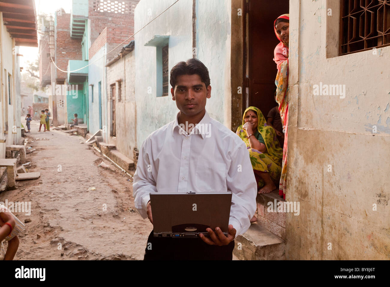 Indien, Uttar Pradesh, Agra, indischer Geschäftsmann in Hals Hemd mit Laptop in verfallenen Dorf Einstellung öffnen Stockfoto