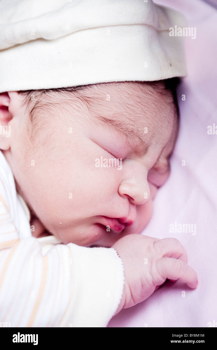 Neugeborenes Baby im Krankenhaus einen Tag alt mit Kappe in seinem Bettchen schlafen Stockfoto