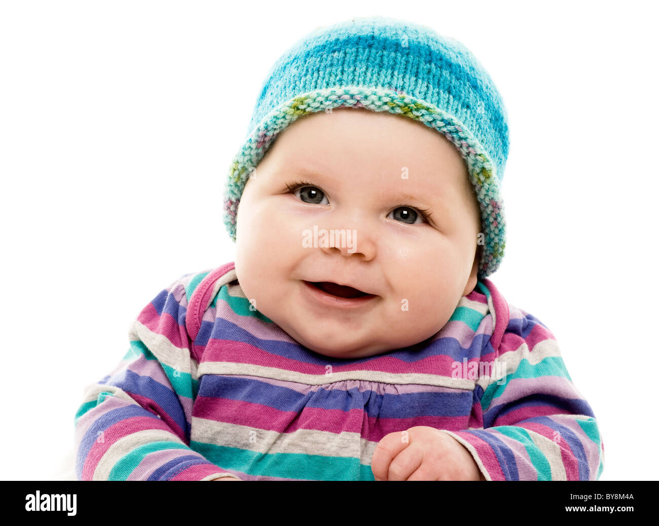 Kopf- und Schulteraufnahme eines kaukasischen Babys in einem knallbunten gestreifte Outfit und türkisfarbenem Hut Stockfoto