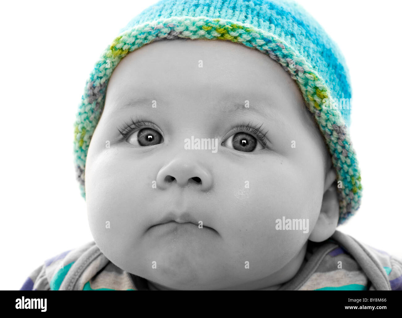 Spot farbige monochrome Kopfaufnahme eines Babys mit türkisfarbenem Strickmütze, das aus der Schussaufnahme schaut Stockfoto