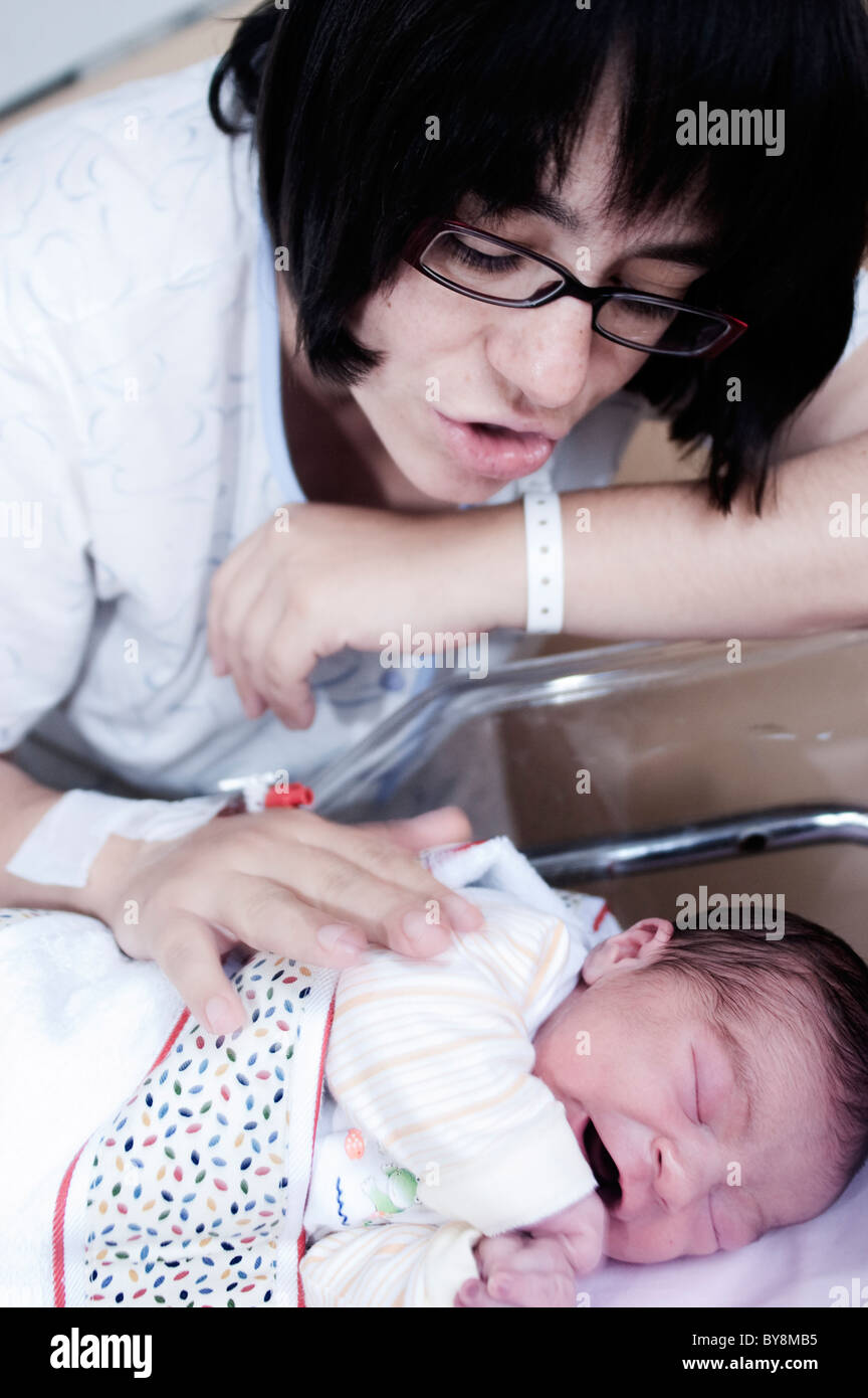 Eine Mutter ihr Baby in eine Krippe Hospìtal betrachten Stockfoto