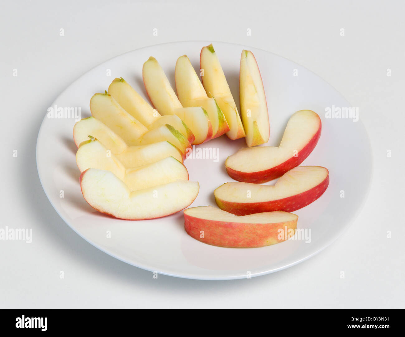 Essen Obst Äpfel Scheiben reifer Apfel auf einem runden weißen Teller auf einem weißen Hintergrund. Stockfoto