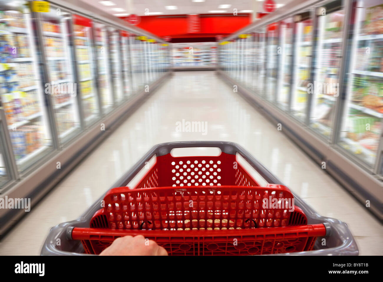 Ein Fast-Food-Konzept Bewegungsunschärfe Schuss von einem Einkaufswagen geschoben hinunter den Gang eines Supermarktes Stockfoto