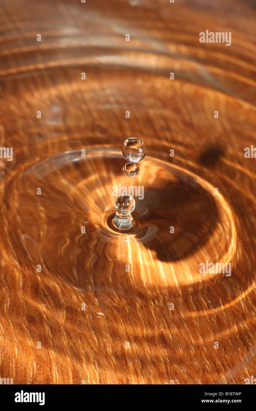 Wassertropfen spritzt gegen einen hölzernen Hintergrund Stockfoto