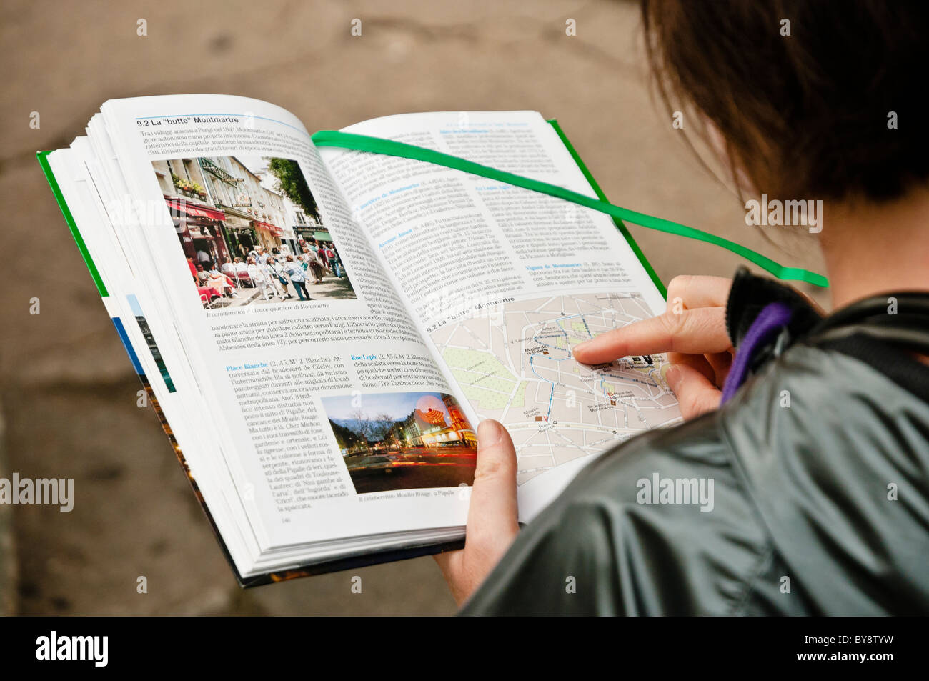 Ein Tourist auf der Suche hier Karte in einem Buch der Reisenden in Montmartre, Paris, Frankreich Stockfoto