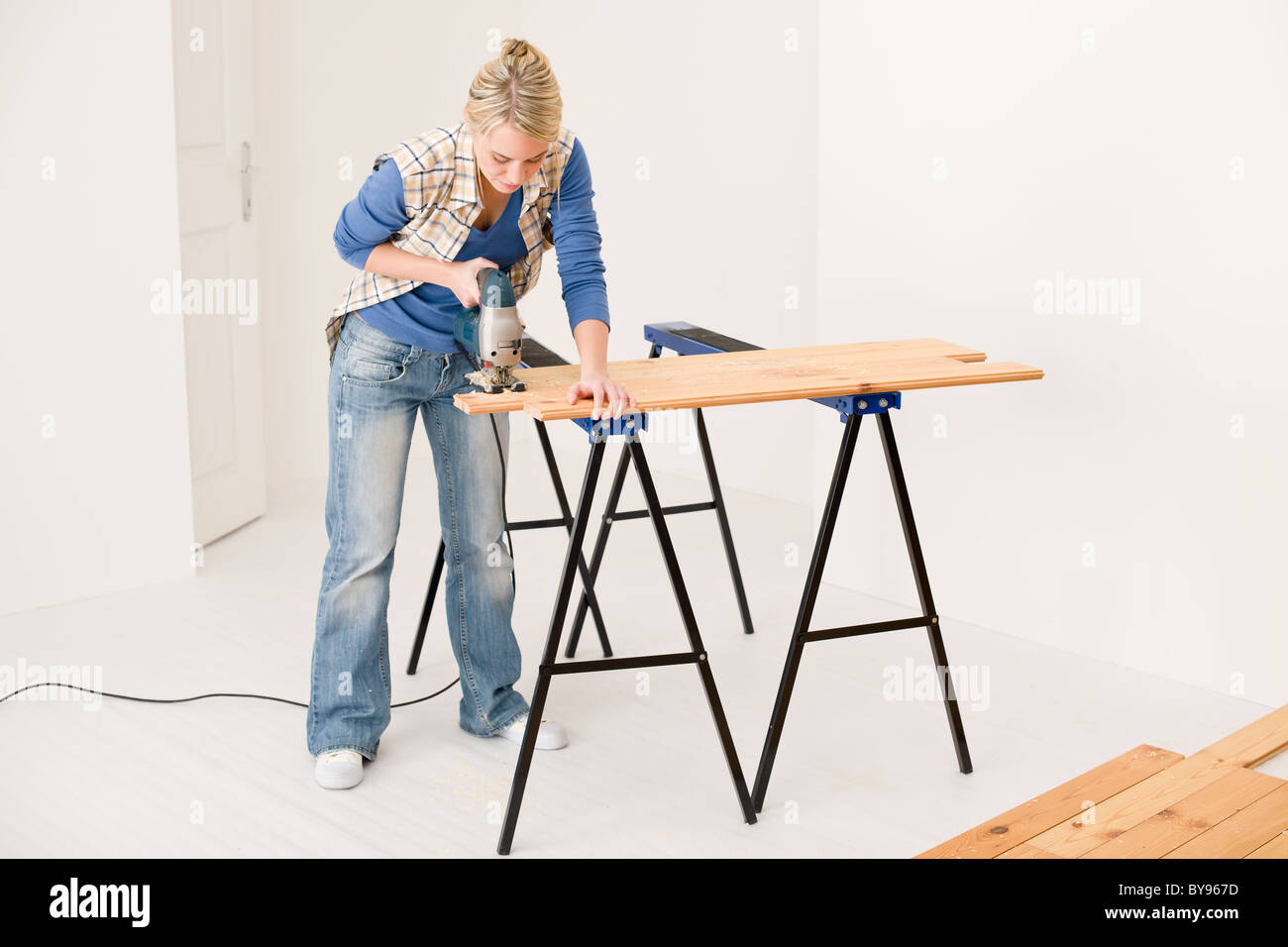 Heimwerken - Handywoman schneiden Holzboden mit Stichsäge Stockfoto