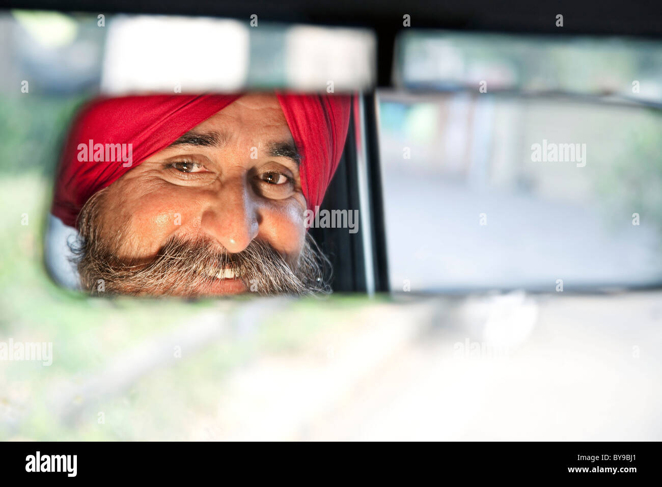 Sikh Taxifahrer Blick in den Rückspiegel Stockfoto