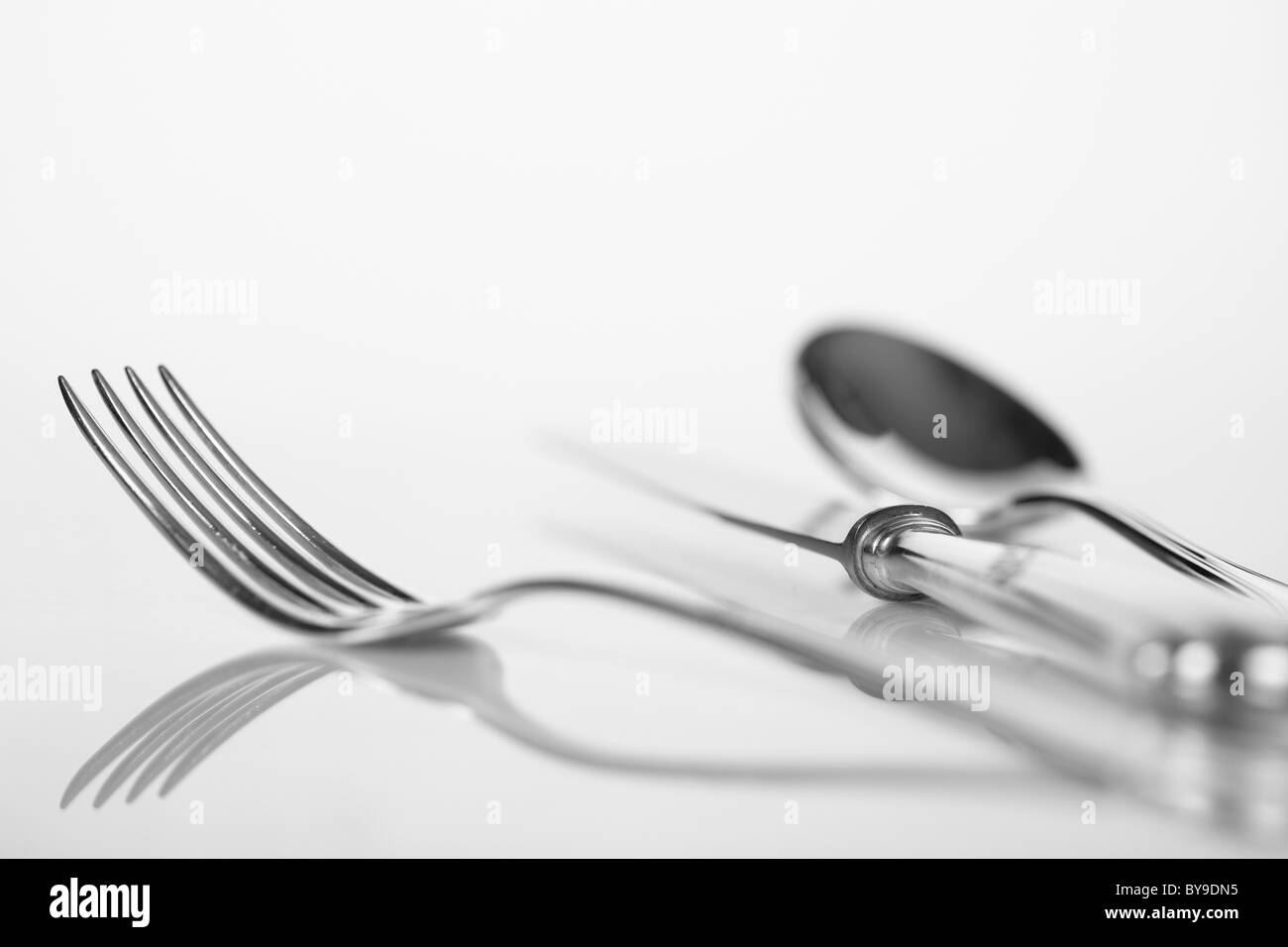 Löffel, Gabel und Messer auf einer reflektierenden Oberfläche, Besteck Stockfoto