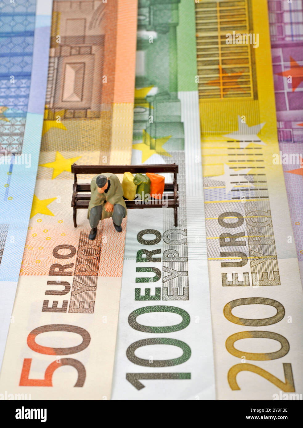 Verschiedenen Euro-Banknoten mit einem Miniatur-Wert von ein Obdachloser auf einer Parkbank, symbolisches Bild der Euro-Krise Stockfoto