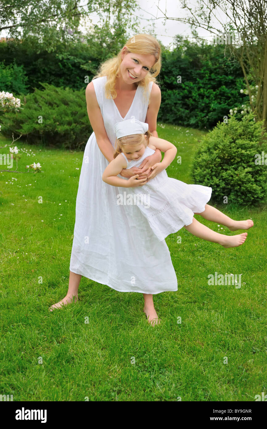 Glückliche junge Mutter und Tochter spielen in Wiese Stockfoto