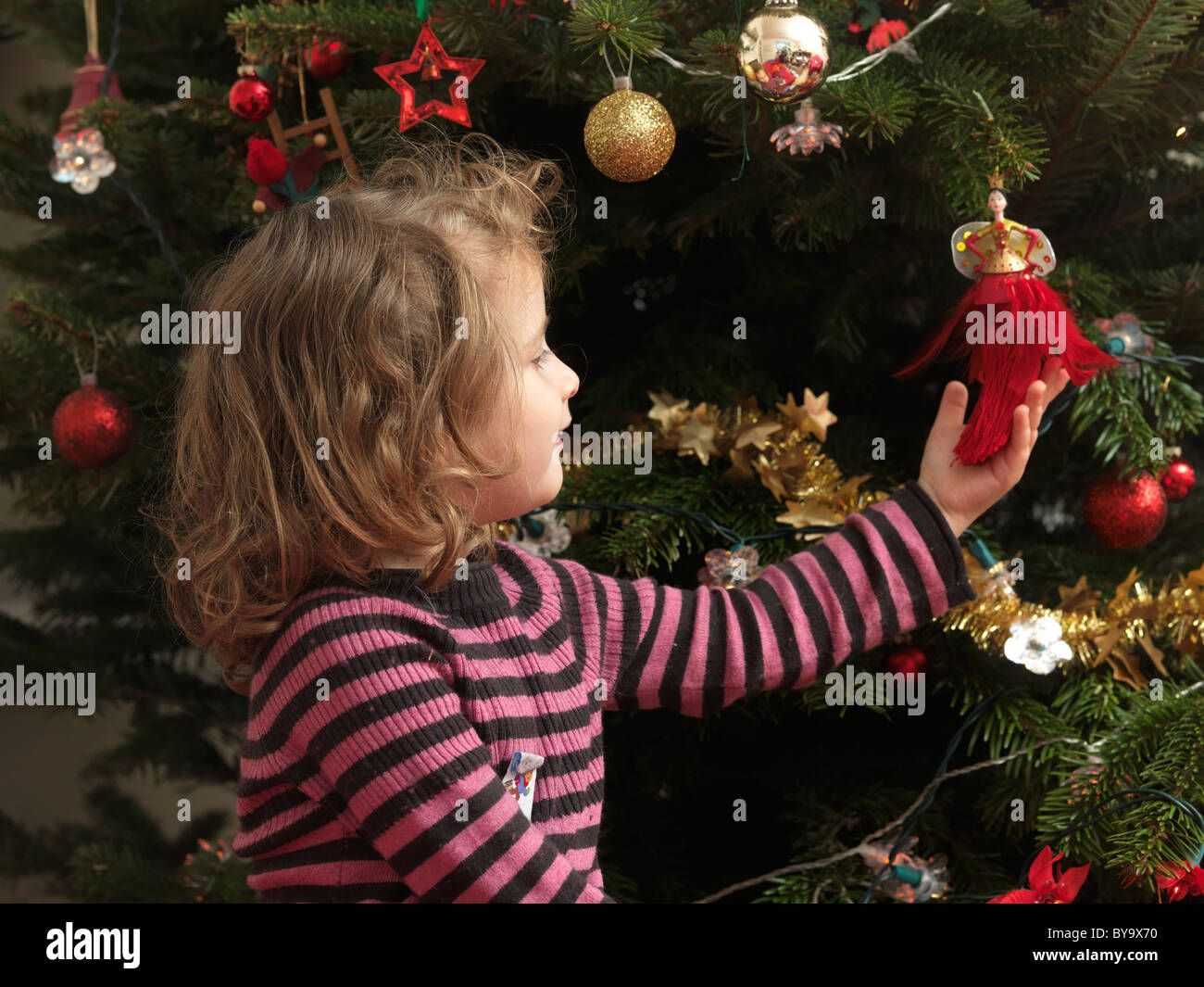 Junges Mädchen Blick auf Dekoration am Weihnachtsbaum England Stockfoto