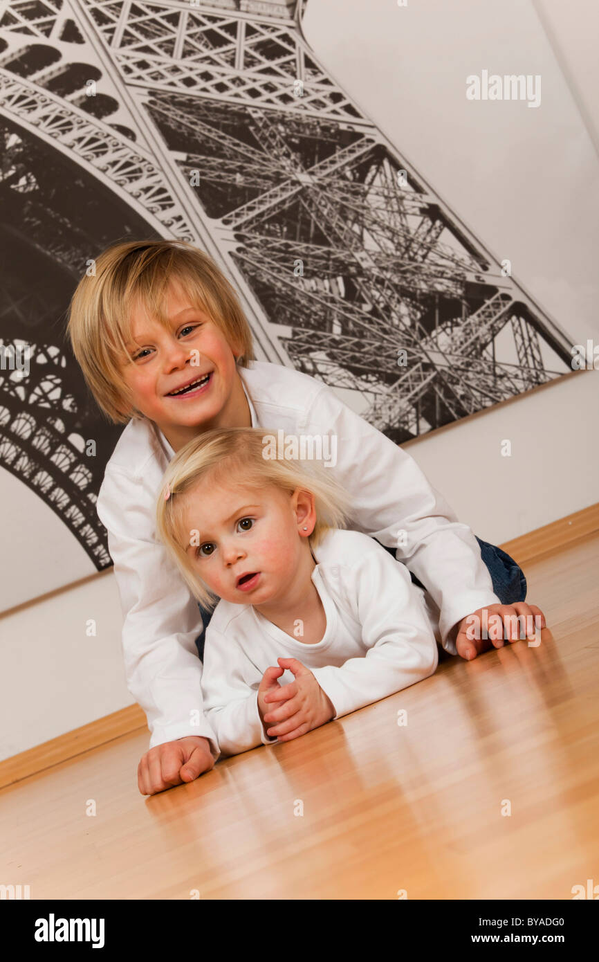 Junge, 7 Jahre, und Mädchen, 1,5 Jahre, auf dem Boden liegend Stockfoto