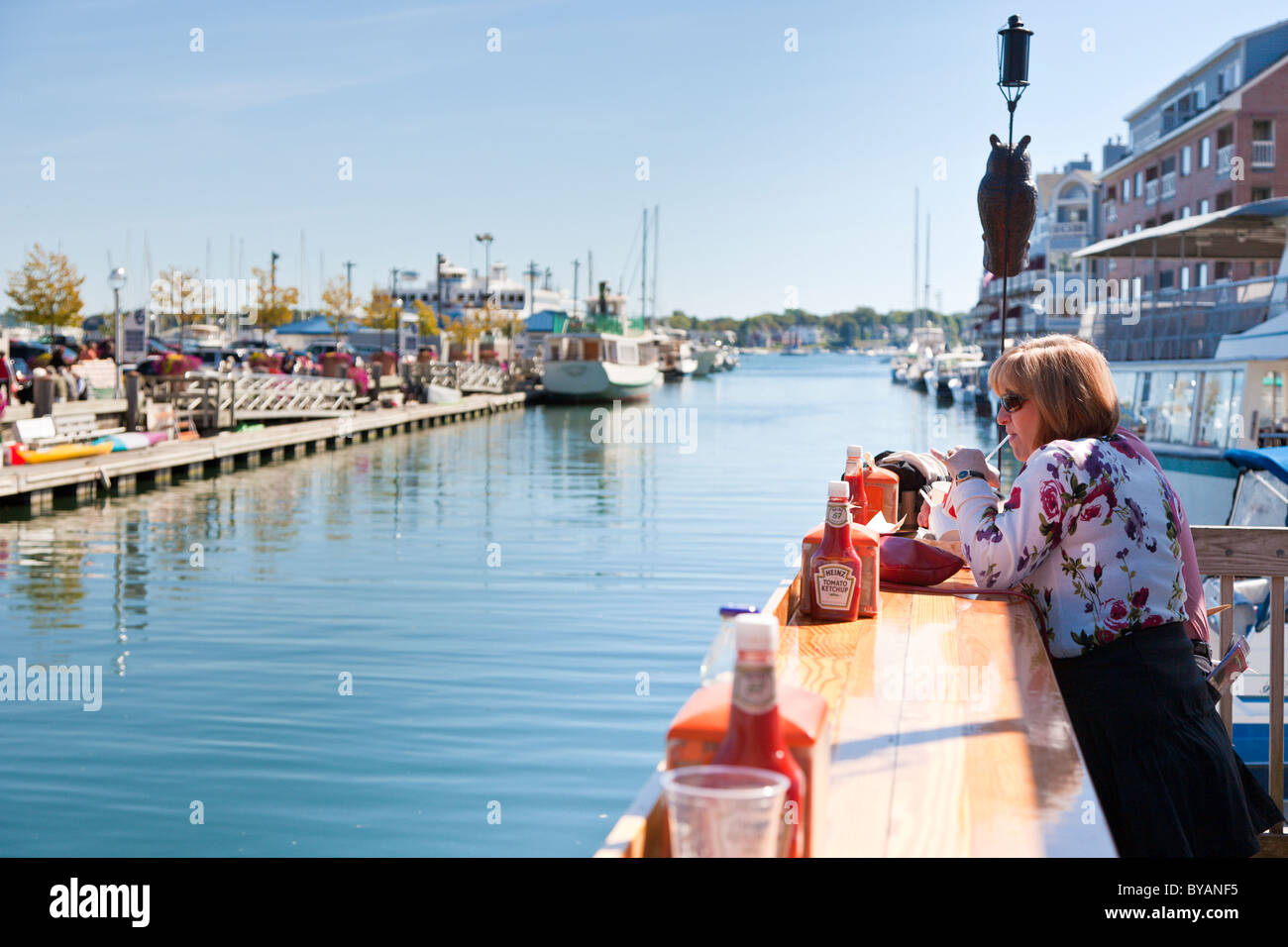 Mittlere gealterte Frau Essen und trinken draußen im Restaurant am Kai in Portland, Maine Stockfoto