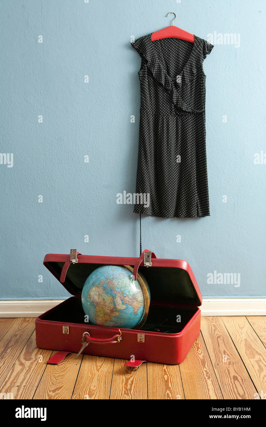 Globus in einem Koffer, Kleid hängen auf einem Kleiderbügel, symbolisches Bild für Reisen, Urlaub, Weltreise Stockfoto