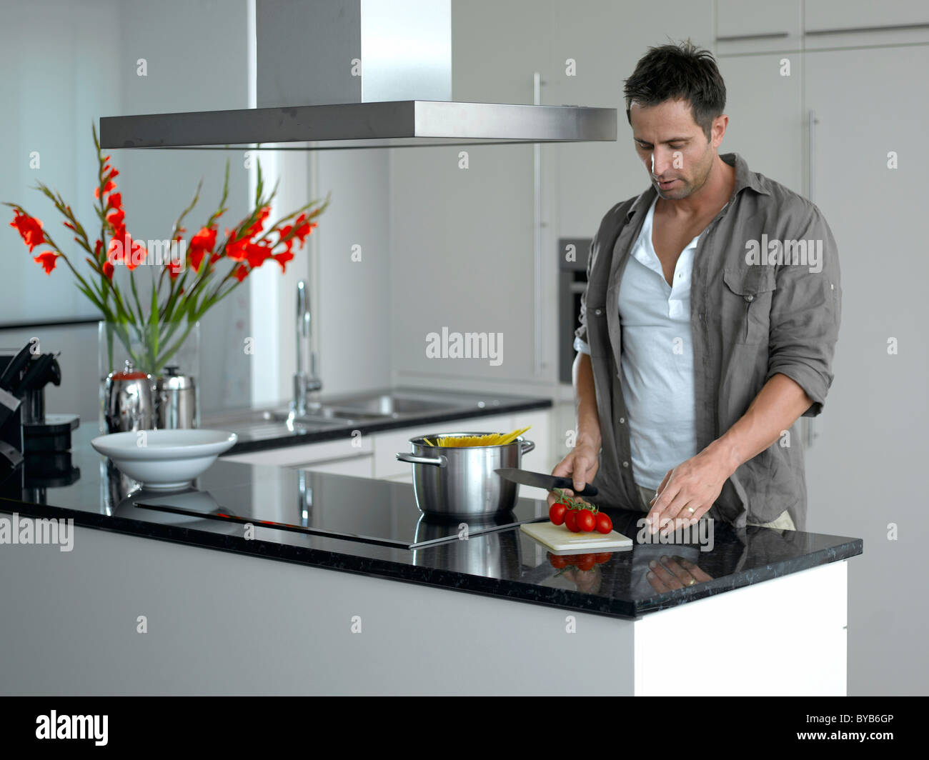 Mann schneiden Tomaten in einer modernen Küche Stockfoto