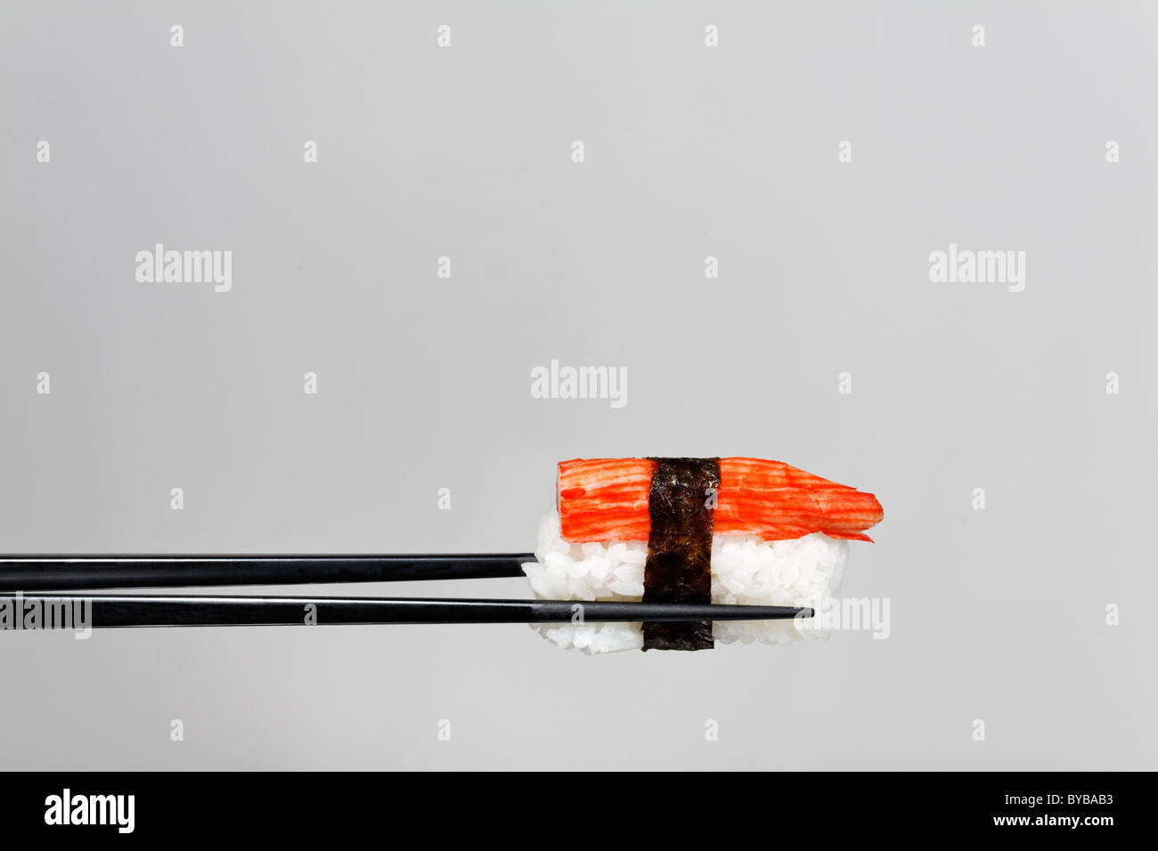 Schwarzen Stäbchen halten Nigiri Sushi mit Hummerfleisch, umhüllt mit nori  Stockfotografie - Alamy