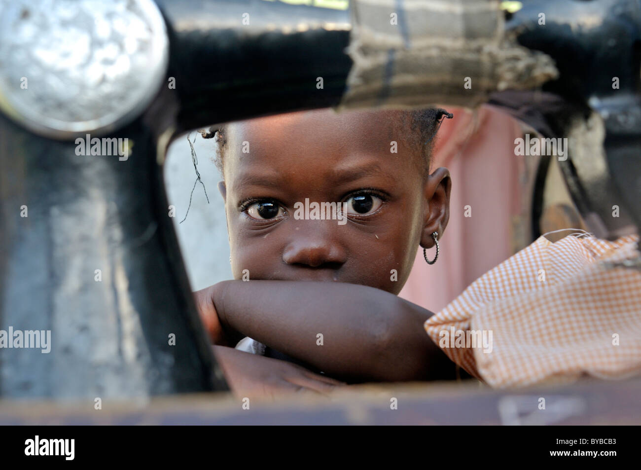Kleines Mädchen versteckt sich hinter eine alte mechanische Nähmaschine, Lager für Opfer des Erdbebens in Januar 2010 Stockfoto