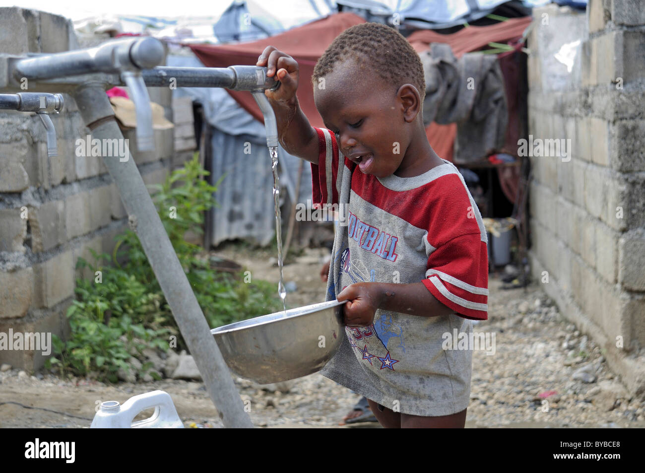 Kleiner Junge holen Trinkwasser von einer Spannungsquelle in einem Lager für Opfer des Erdbebens in Januar 2010 Stockfoto