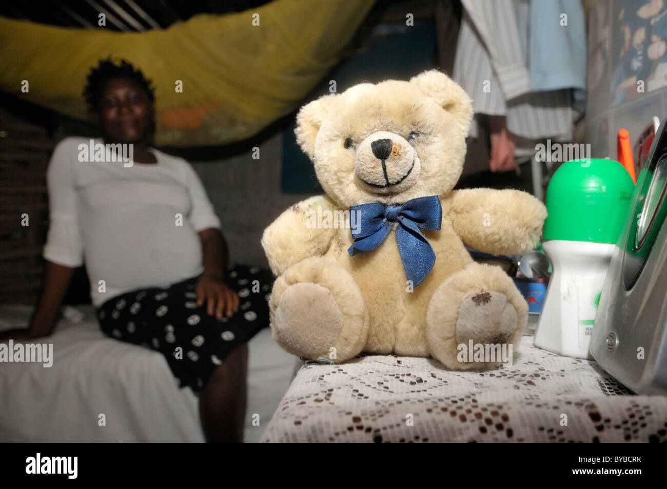 Schwangere Frau, 15 Jahre, sitzt auf ihrem Bett mit einem Teddy-Bären, Dorf L'Acul in der Nähe von Leogane, Haiti, Karibik, Mittelamerika Stockfoto