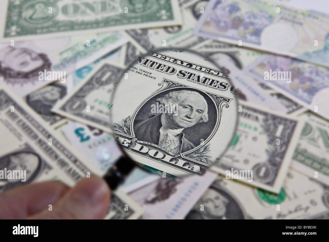 Beobachtung des US-Dollars gegenüber anderen Währungen mit einer Lupe Stockfoto