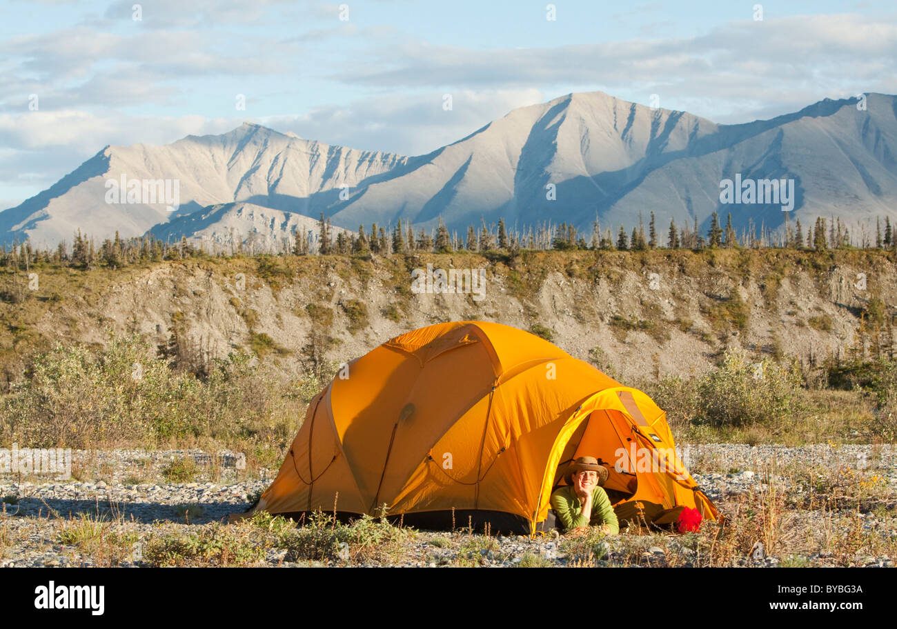 Junge Frau, die aus einer Expedition Zelt, arktische Tundra, camping, Mackenzie Mountains, Wind River, Yukon-Territorium Stockfoto