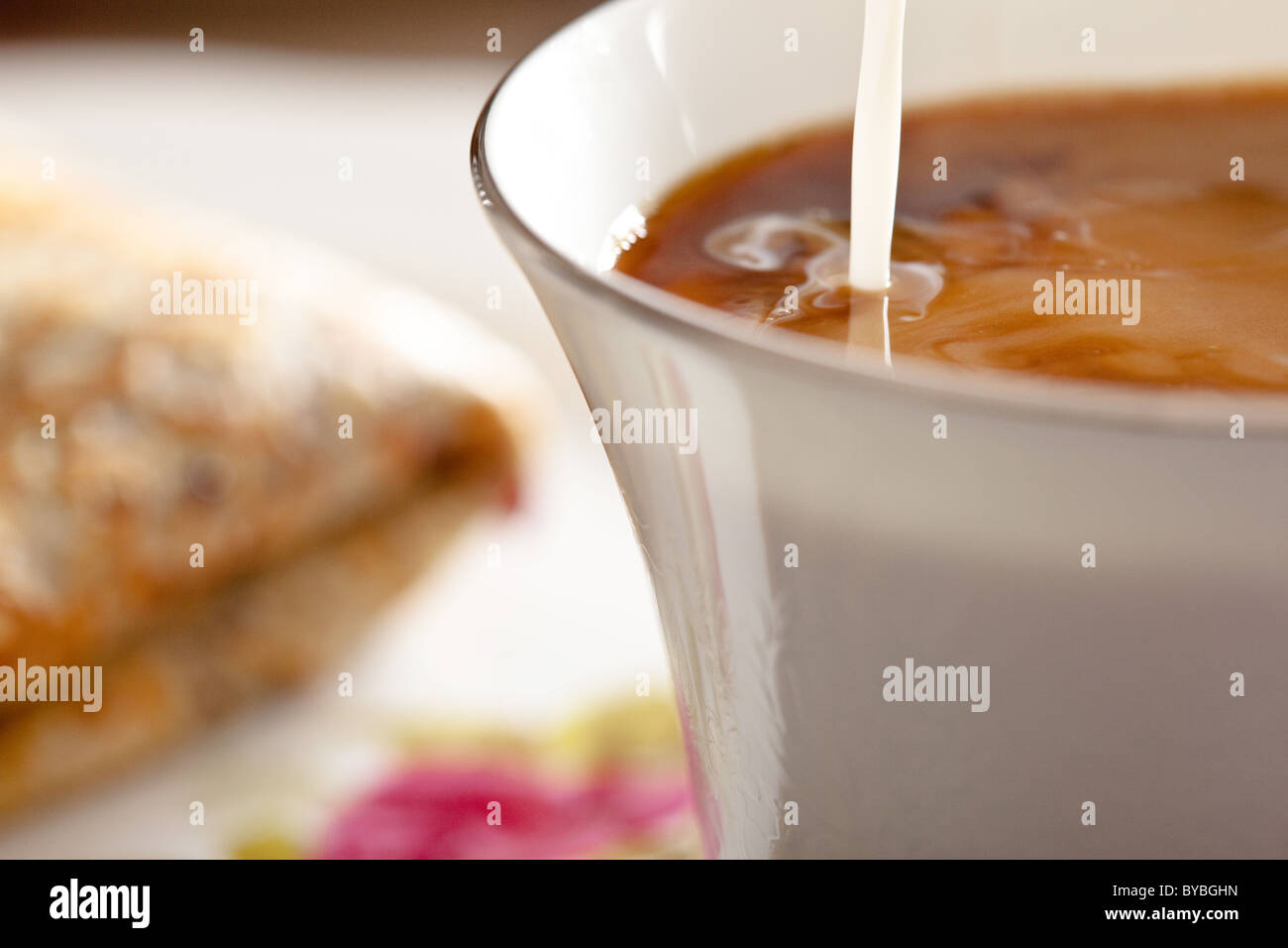 Milch hinzugefügt, um eine Tasse Kaffee, eine isländische Pfannkuchen zweimal mit geschlagener Sahne und Blaubeeren Marmelade neben der Tasse gefaltet. Stockfoto