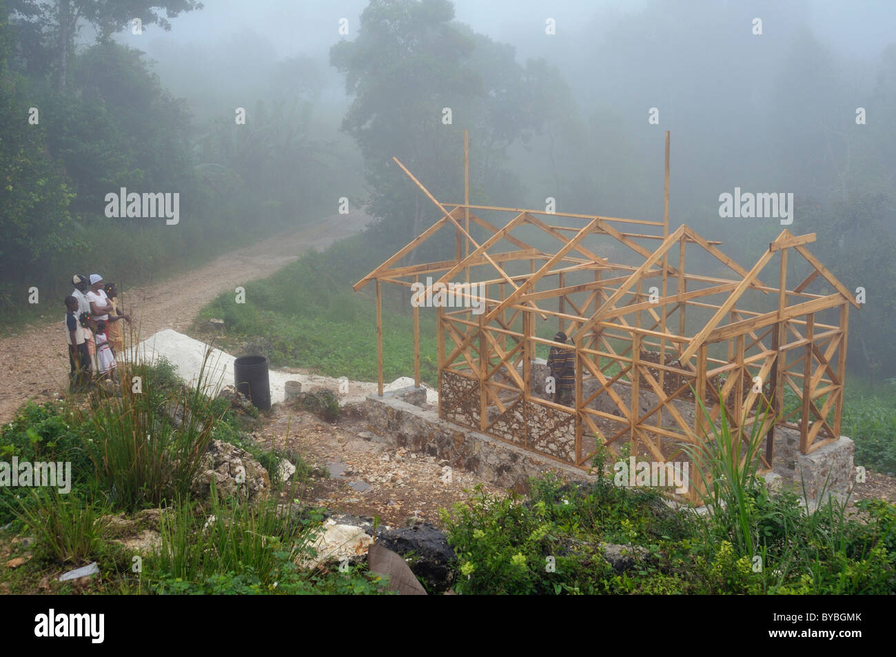 Eine Familie, die Opfer des Erdbebens im Januar 2010 neben ihrem neuen erdbebensichere Haus mit Fachwerkkonstruktion, die Stockfoto