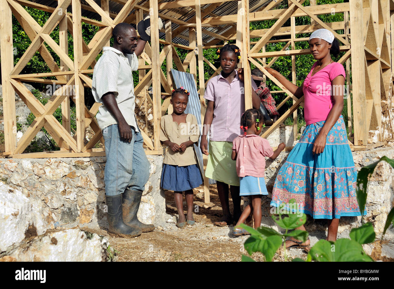 Eine Familie, die Opfer des Erdbebens im Januar 2010 neben ihrem neuen erdbebensichere Haus mit Fachwerkkonstruktion, die Stockfoto