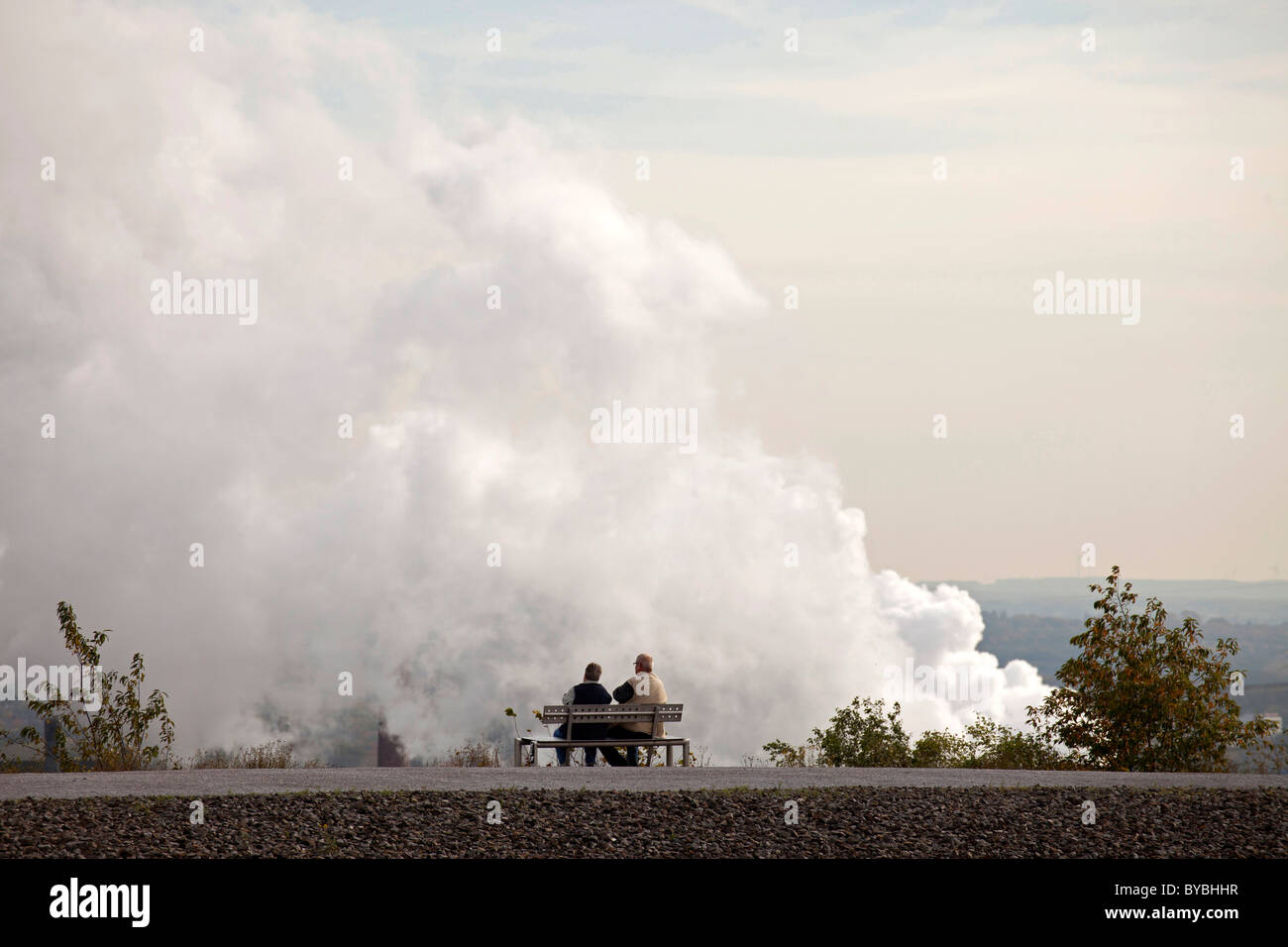 Paar auf einer Bank vor Luftverschmutzung aus einem Kraftwerk in Bottrop, Ruhrgebiet, Nordrhein-Westfalen Stockfoto